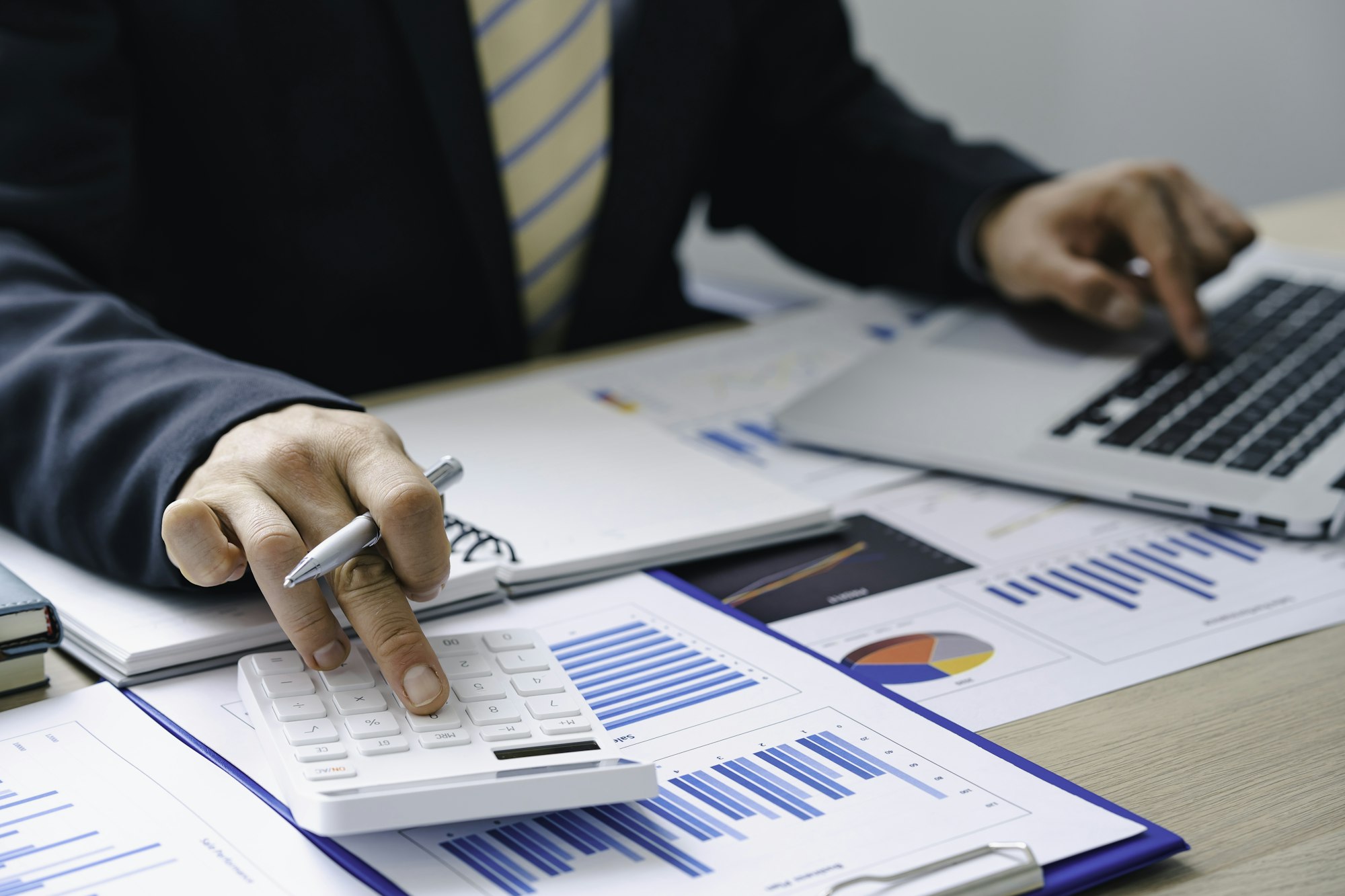 Businessman presses a calculator to calculate. and holding a pen and paper chart summary pointing ou